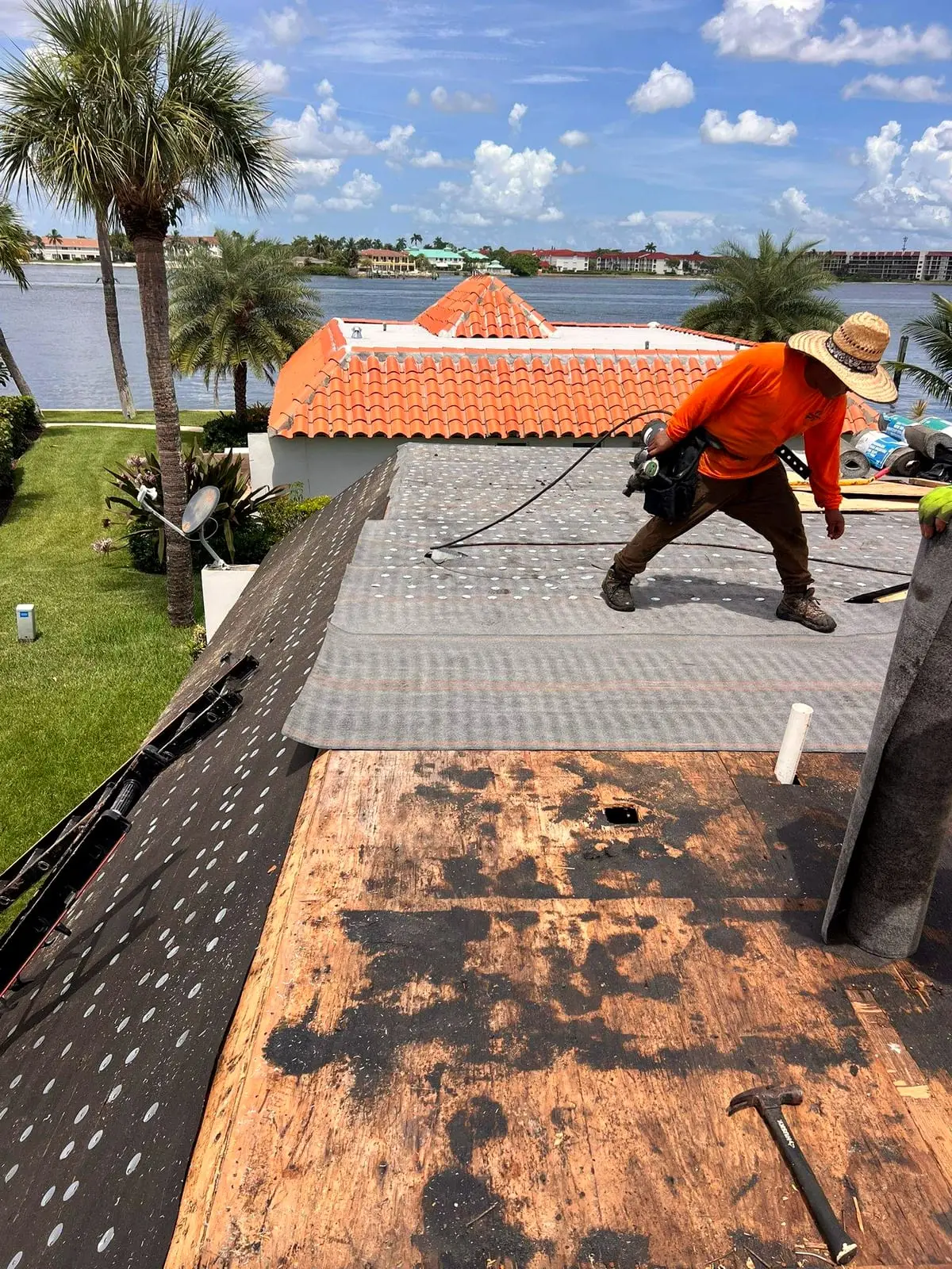 Roofer fastening underlayment over the roof deck with rows of cap nails