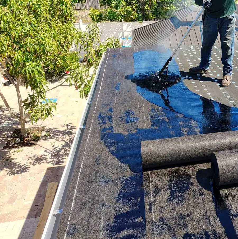 White gutter running along the edge of a flat roof during re-roofing