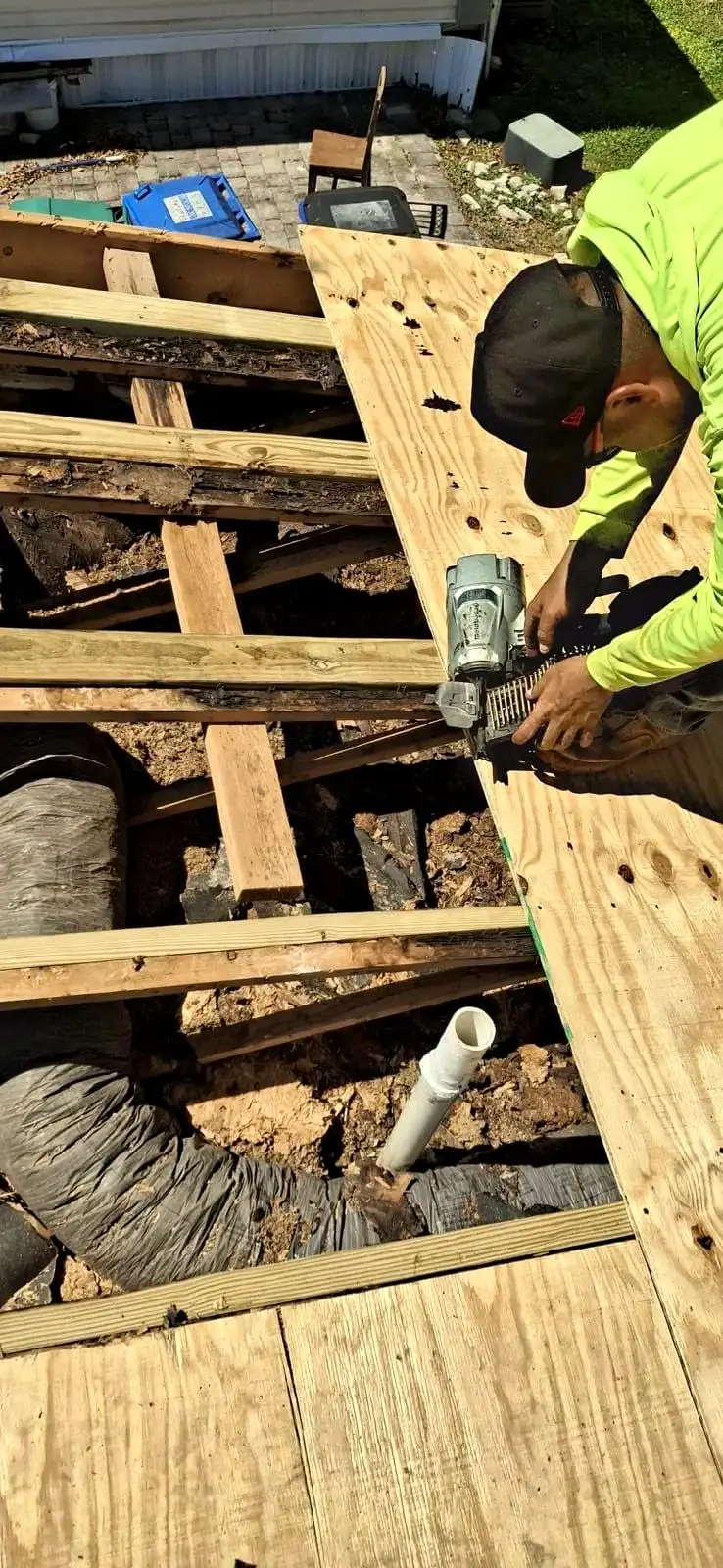 Roofer nailing new plywood over the rafters where rotted decking was cut out